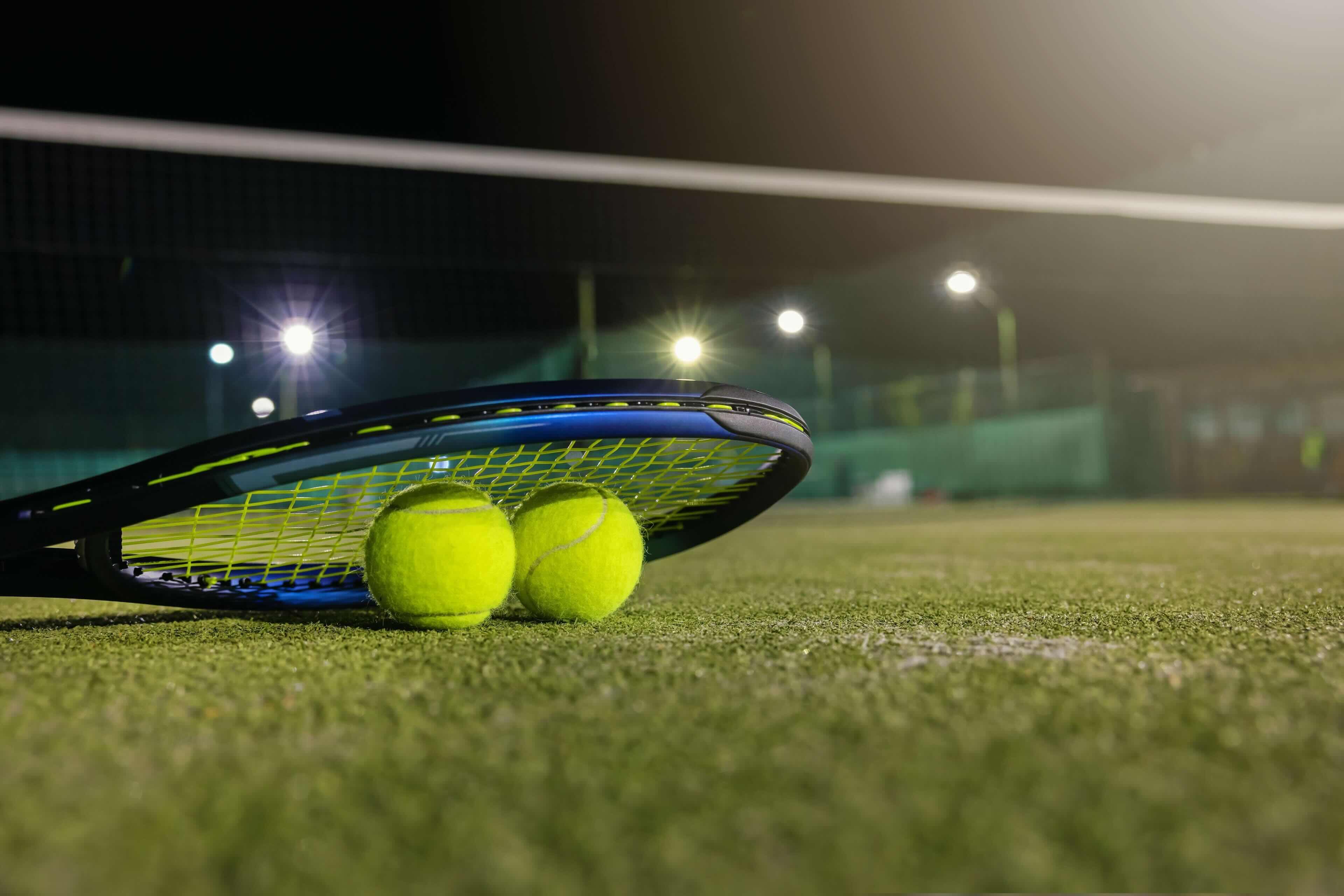 Splash image of a racquet sitting over 2 tennis balls.